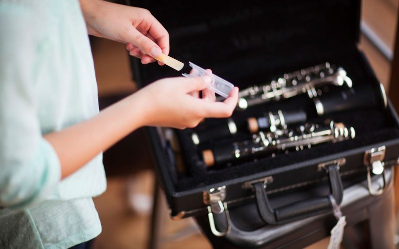 A player fitting a reed to a clarinet mouthpiece beside an open case