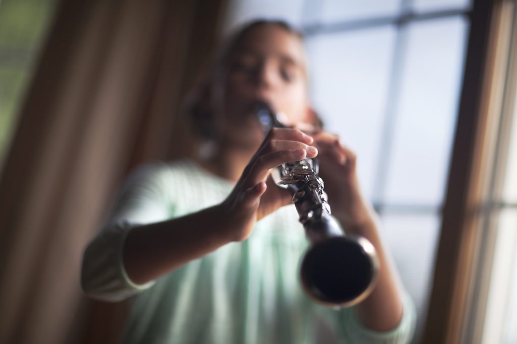 Young musician playing the clarinet by the window.