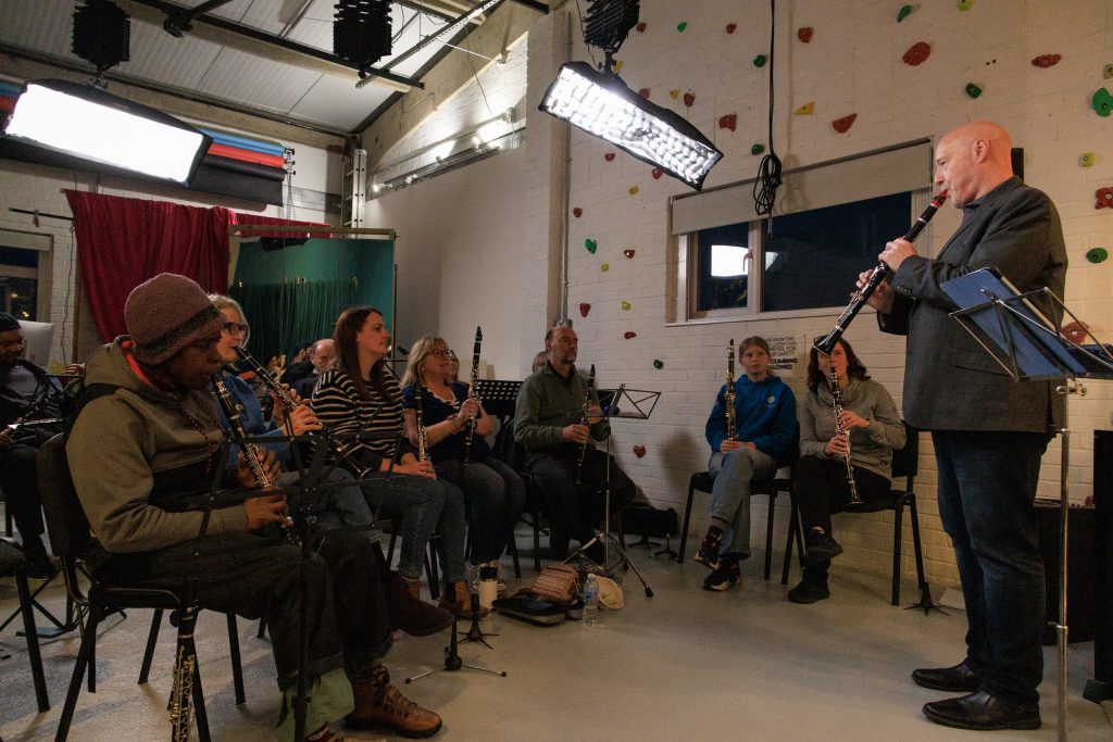 Clarinet Player, Simon Bates, standing in front of a group of people all playing clarinets.